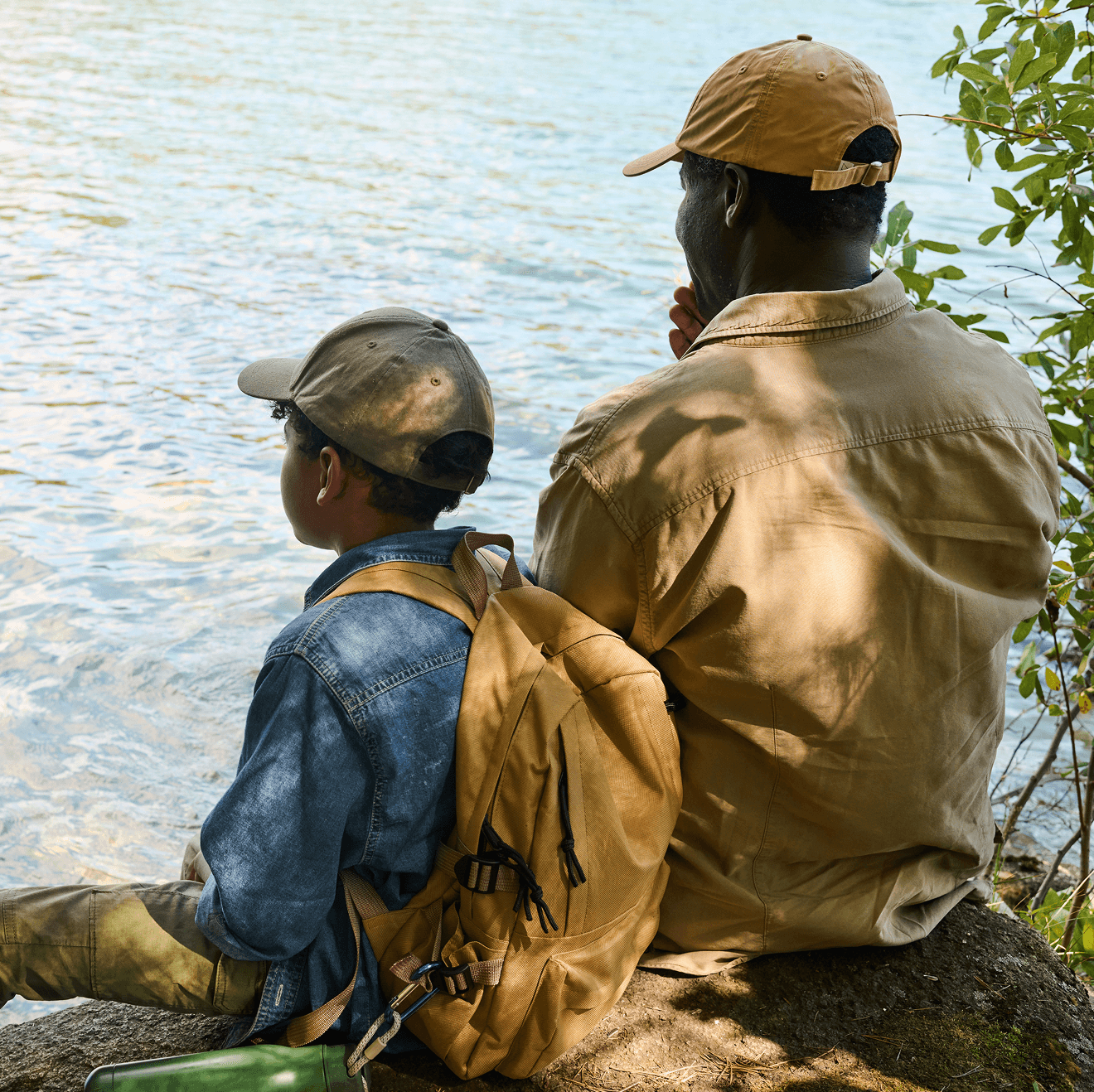 An adult and a child sitting together by the water’s edge