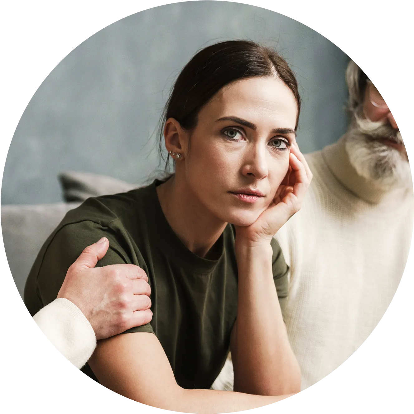 Professional portrait photograph of a woman with dark hair styled back, wearing an olive green shirt, with her hand thoughtfully placed against her face while gazing at the camera